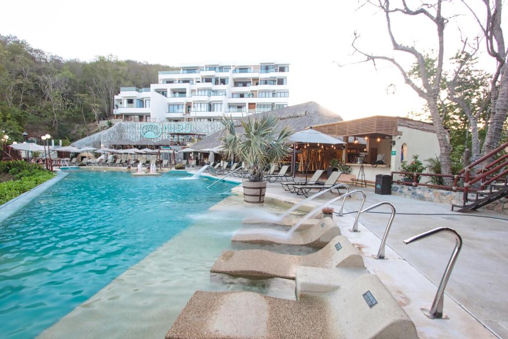 a swimming pool with a hotel in the background at Nirú Ocean Suites by Binniguenda in Santa Maria Huatulco