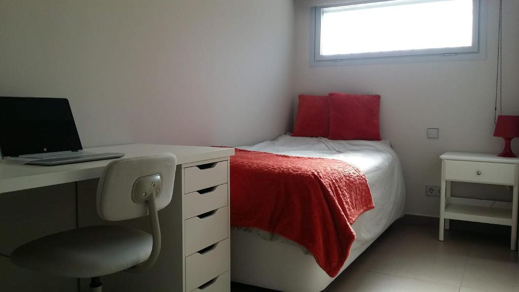 Schlafzimmer mit einem Schreibtisch und einem Bett mit einer roten Decke in der Unterkunft LARGE HOUSE & POOL near the beach and Barcelona in Alella