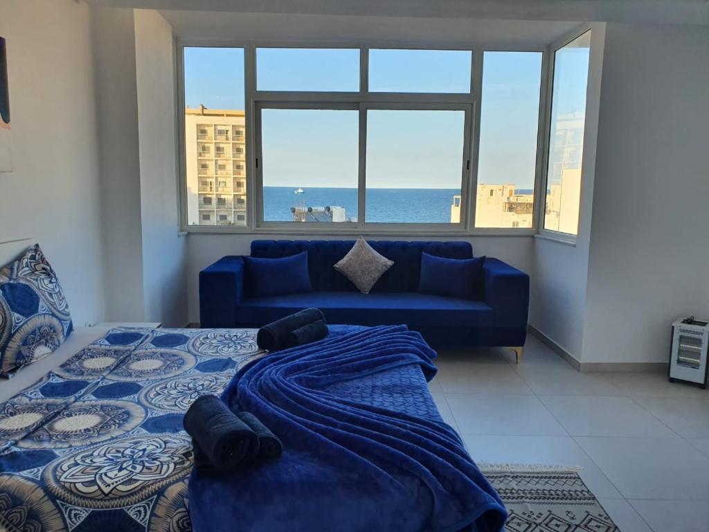 een slaapkamer met een blauw bed en een blauwe bank bij Stunning Penthouse with Sea and Castle View (2BDR) in Sousse