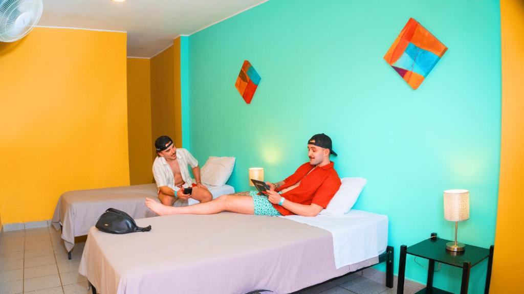 two people sitting on beds in a room at Wild Rover Huacachina in Ica