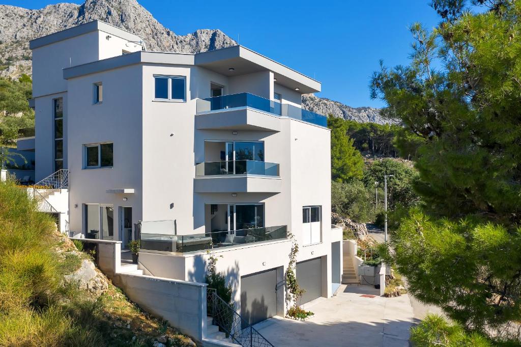 a white house with a mountain in the background at Luxury Apartments Podgora in Podgora