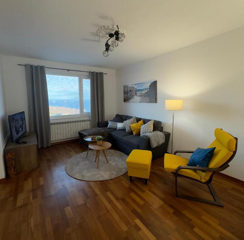 a living room with a blue couch and yellow chairs at Kakavanen’s Sea View apartment in Balchik