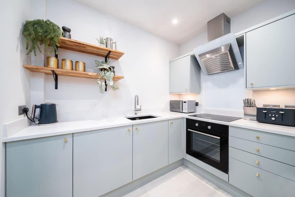 una cocina blanca con armarios blancos y un aparato negro en Charming Granby Flat, en Harrogate