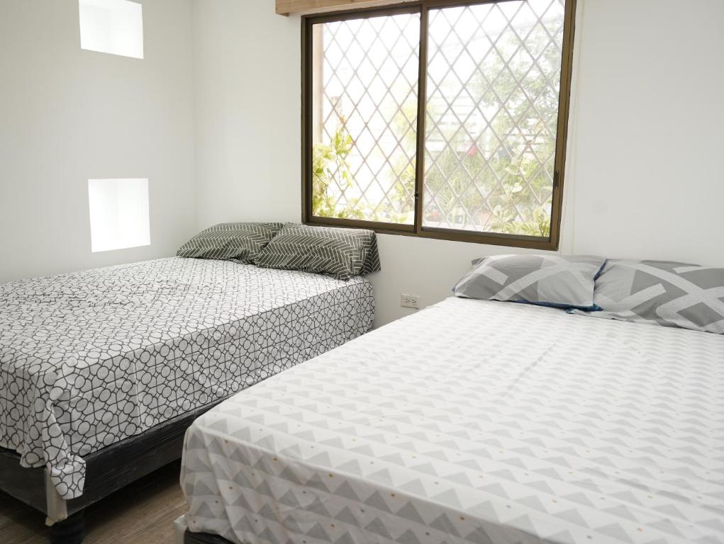 een slaapkamer met 2 bedden en een raam bij Suite departamento al pie de la playas con Aire acondicionado in Playas