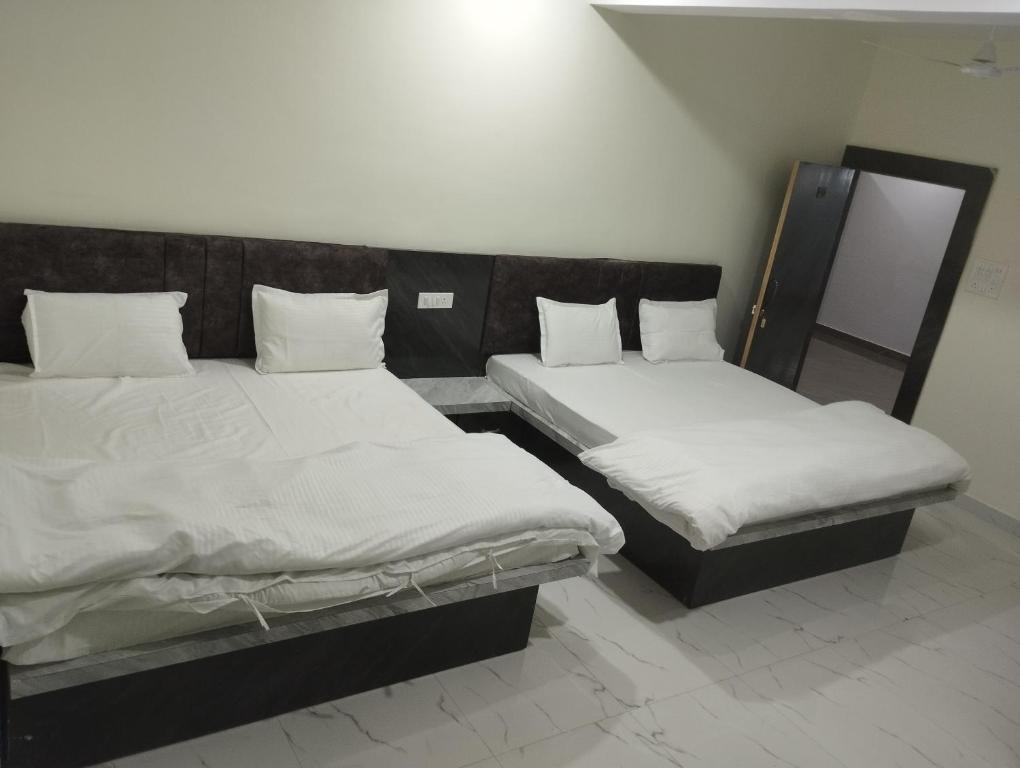 two beds in a room with white sheets and pillows at Hotel anand shree in Hoshangābād