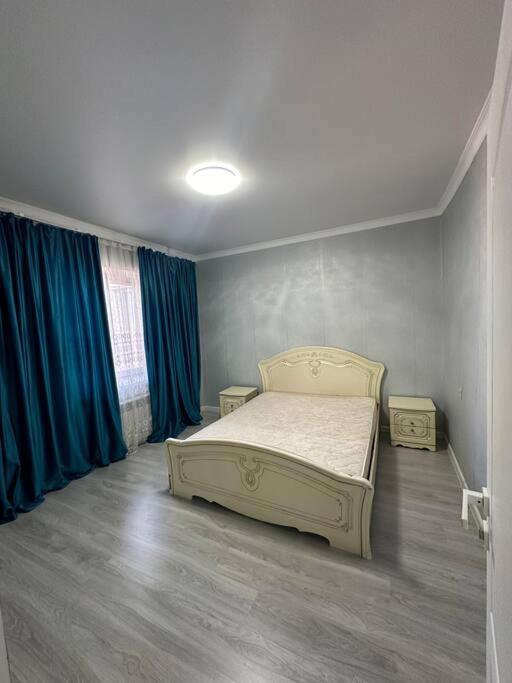 1 dormitorio con 1 cama y cortinas azules en Элитная 2-х комнатная квартира, en Shymkent