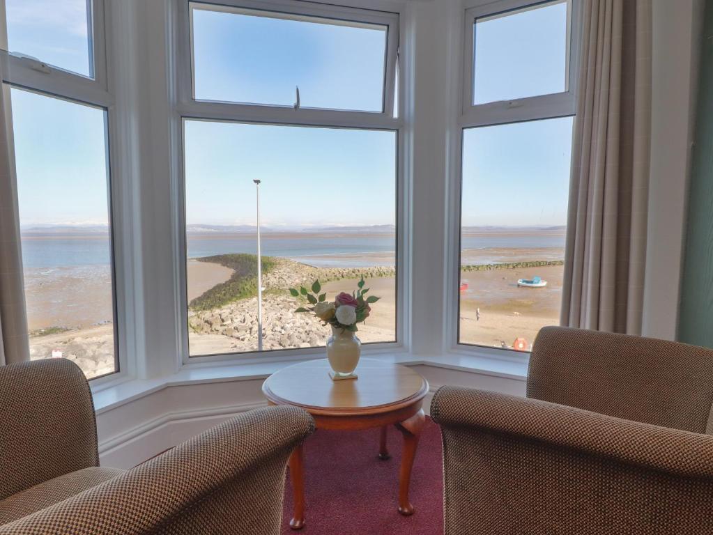 a room with two chairs and a table with a vase of flowers at Eden Bay Retreat in Morecambe
