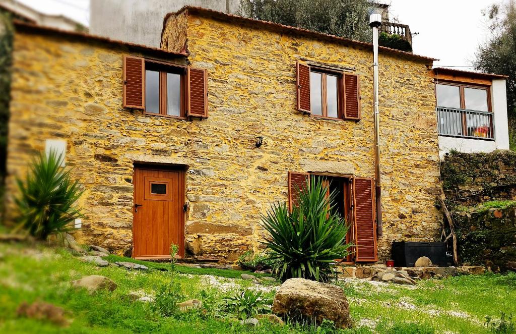 una vecchia casa in pietra con porta e finestre in legno di PampiHouse a Pampilhosa da Serra