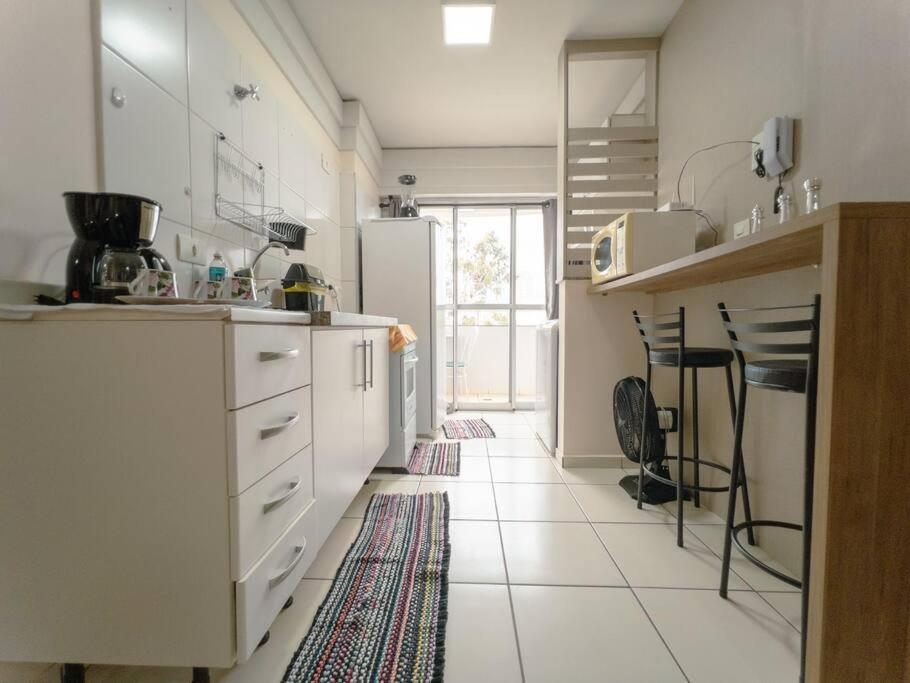  La cuisine est équipée de placards blancs et d'un réfrigérateur. dans l'établissement Apartamento Wifi Smart - CID517A, à Maringá