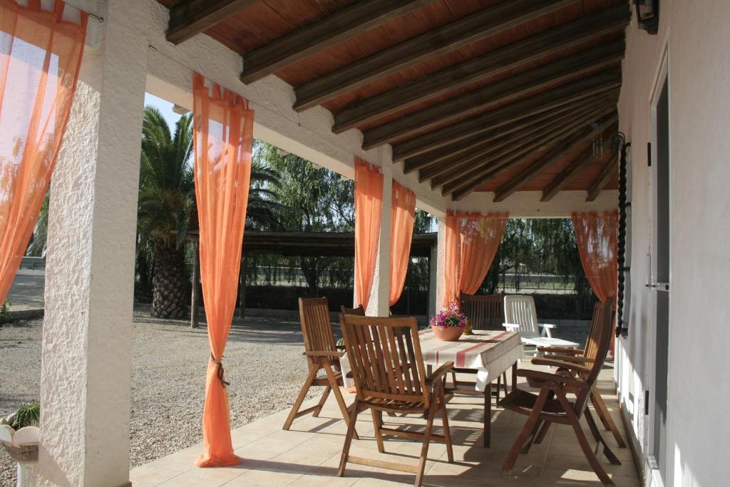 una mesa y sillas en un patio con cortinas naranjas en La Casilla, en Deltebre