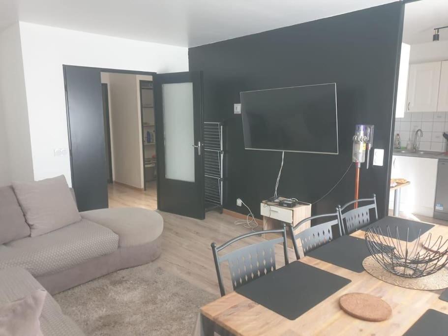 ein Wohnzimmer mit einem Sofa und einem Flachbild-TV in der Unterkunft Duplex de standing in Anzin