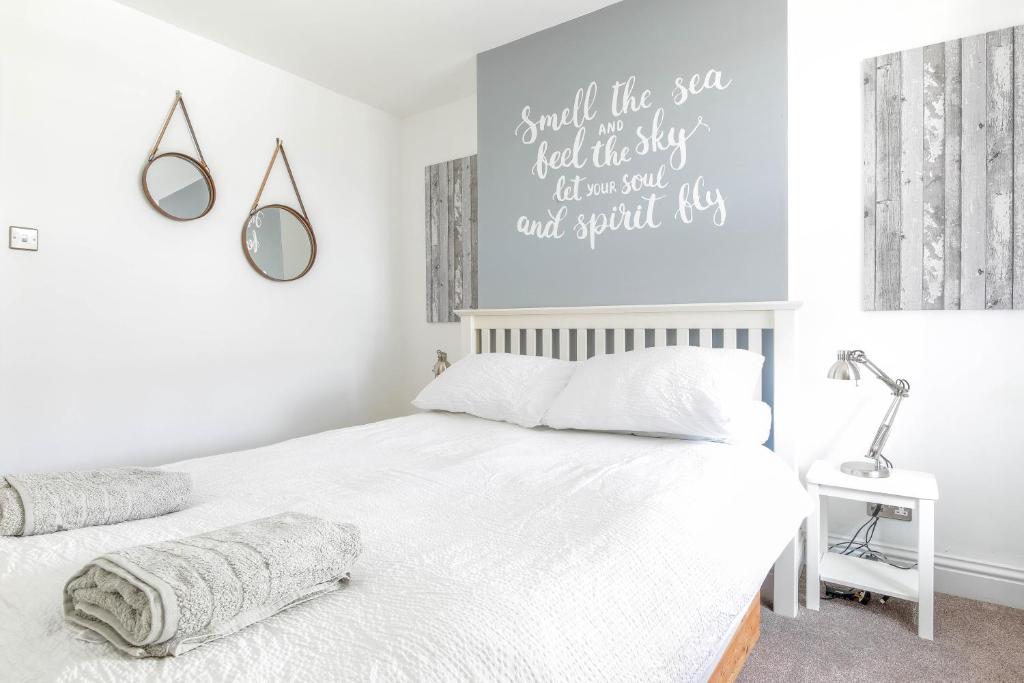 a bedroom with a white bed and a mirror at Shell Cottage in Whitstable