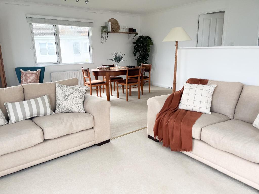 a living room with two couches and a table at Peaceful Riverside Lodge in Christchurch
