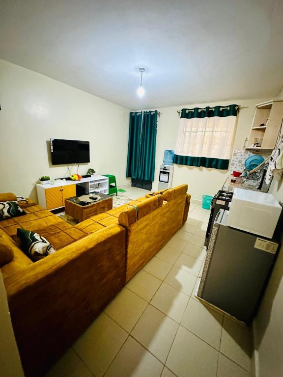 ein Wohnzimmer mit einem großen Sofa und einem TV in der Unterkunft Nuna house in Nairobi
