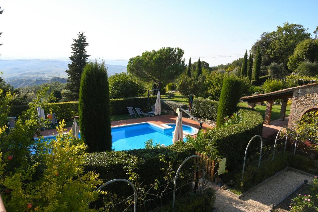 una piscina en un jardín con arbustos y árboles en Podere Le Monache, en Montaione