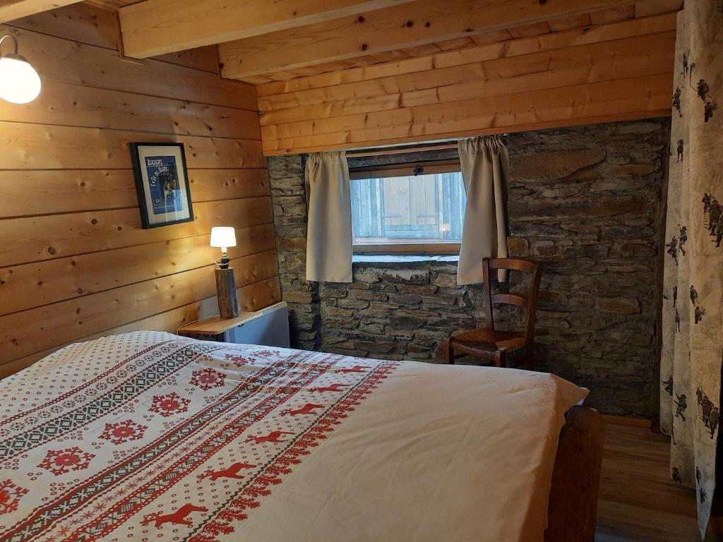 a bedroom with a bed and a chair and a window at Les Granges de la Fontaine in Antignac