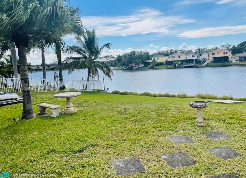 a park with two benches next to a body of water at Cozy lakeside suite with private bath & entrance in Pembroke Pines