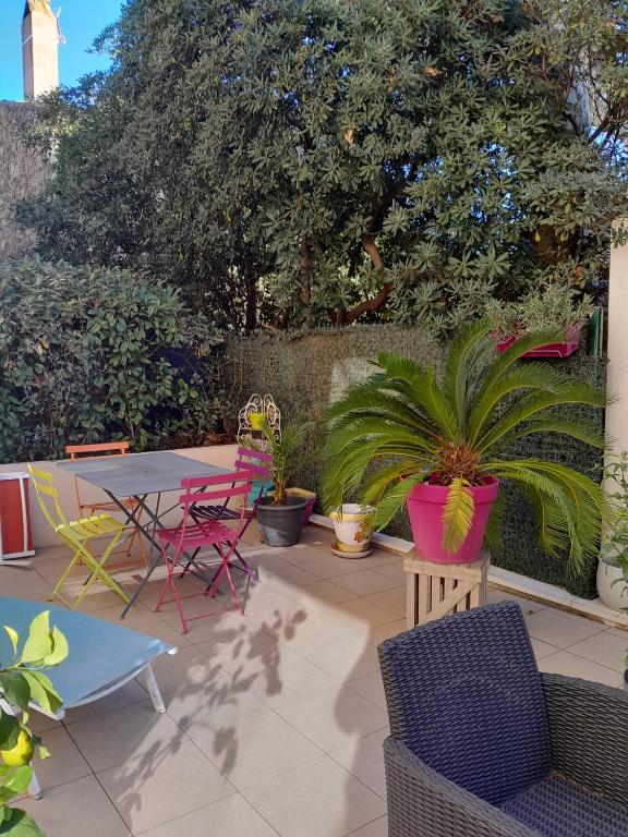 un patio avec une table, des chaises et des plantes dans l'établissement Charmant appartement - Golfe de Saint Tropez - Cogolin, à Cogolin
