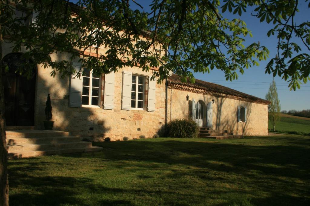 een oud stenen huis met een boom ervoor bij Le Farat Bed & Breakfast in Auvillar