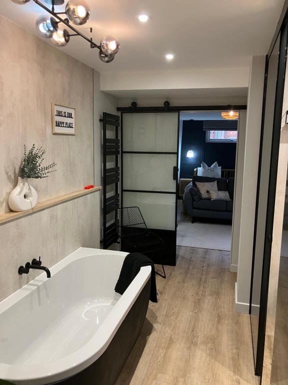 a bathroom with a bath tub and a living room at Abbey Court Guest House in Carlisle