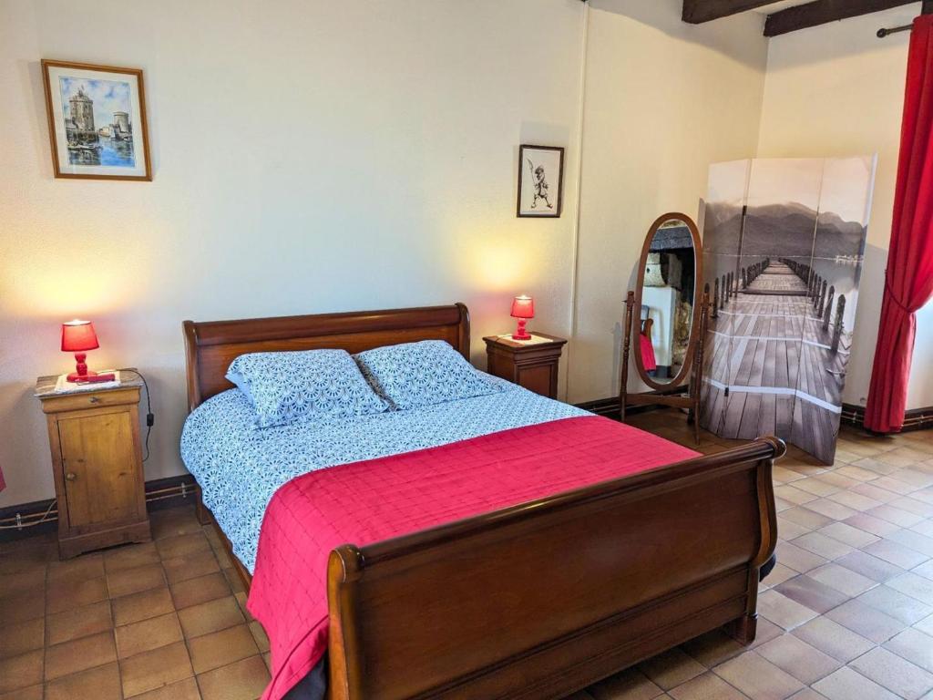 a bedroom with a bed with a red blanket and a mirror at Gîte Cherves-Richemont, 3 pièces, 5 personnes - FR-1-653-205 in Cherves-de-Cognac