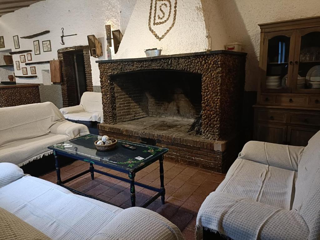 sala de estar con chimenea, 2 sillas y mesa en El Mesón de Higuera de la Sierra, en Higuera de la Sierra