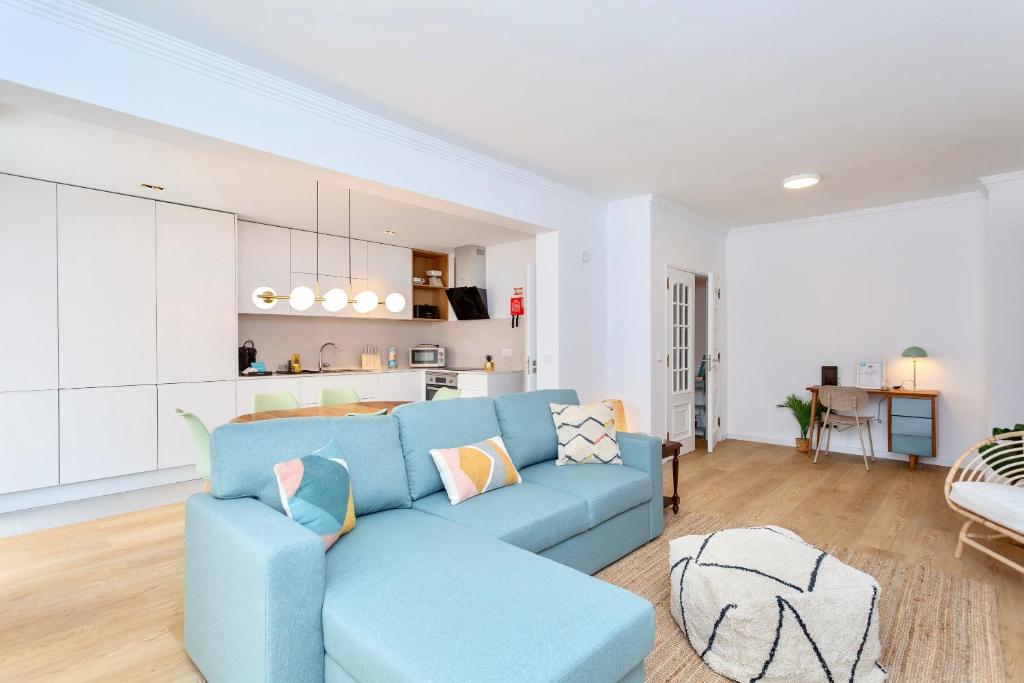 a living room with a blue couch and a kitchen at BeGuest Retiro da Guia in Cascais