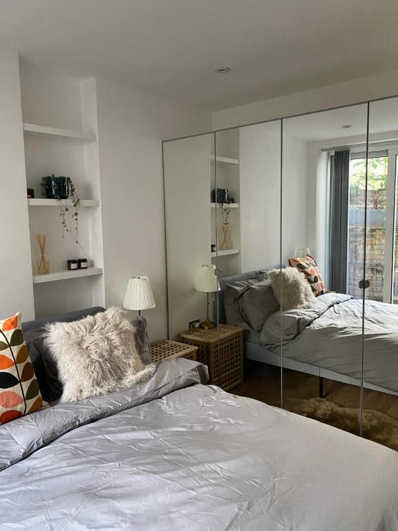 een slaapkamer met 2 bedden en een spiegel bij Stylish Garden Flat in Londen