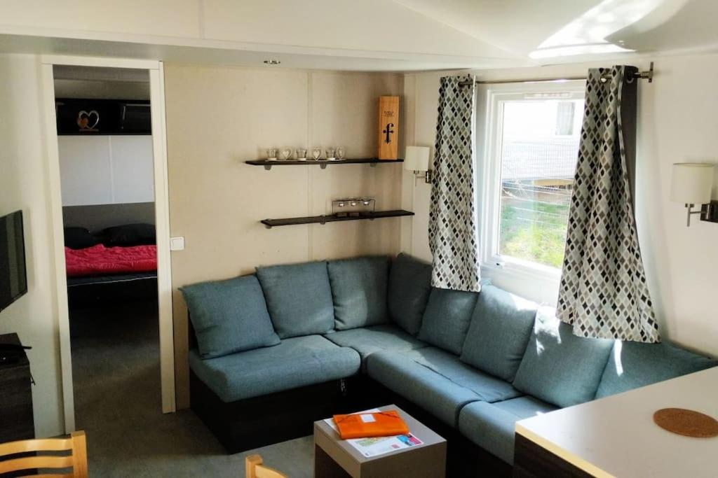 - un salon avec un canapé bleu et une fenêtre dans l'établissement Mobil-home FO 18 à Vias, à Vias