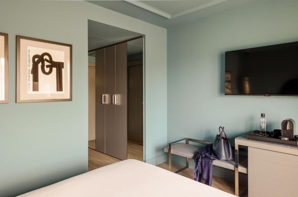 a bedroom with a bed with a mirror and a tv at Hotel Antik San Sebastián in Donostia-San Sebastián