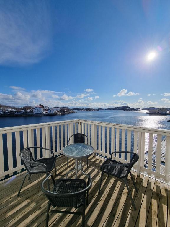a table and chairs on a deck with a view of the water at Apartment with fantastic seaview in Henningsvær. in Henningsvær