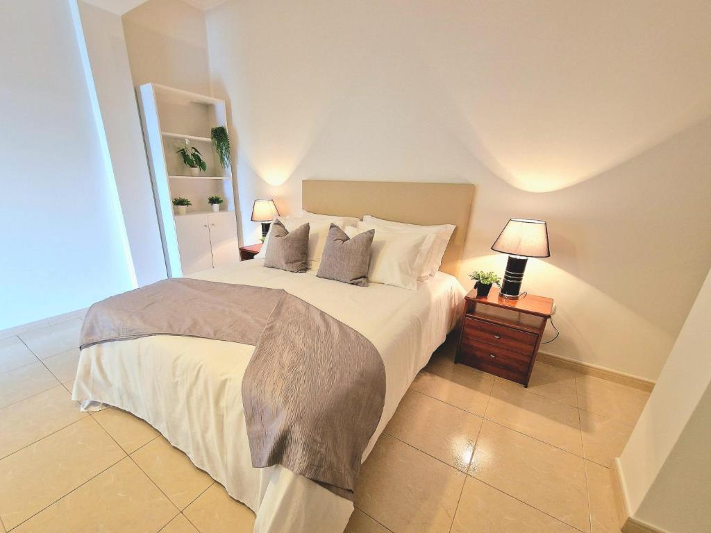 une chambre avec un grand lit blanc avec deux lampes dans l'établissement Sunshine Palace Madeira, à Ponta do Sol