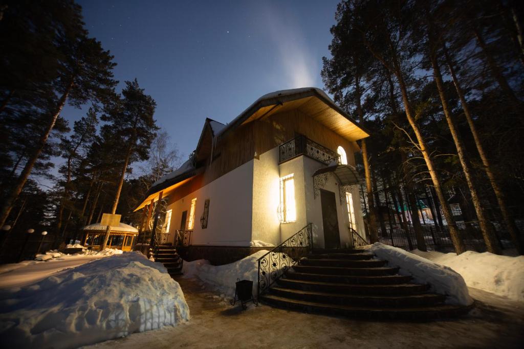 un pequeño edificio con escaleras en la nieve por la noche en "Alatau" Гостевой Дом, en Shchūchīnsk