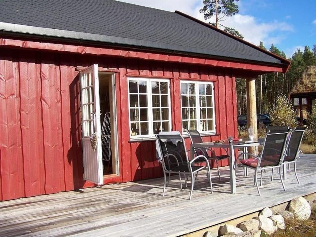 cabina roja con mesa y sillas en la cubierta en Großes Holzferienhaus mit Sauna in der Nähe von Wasser und Skicenter, en Vradal