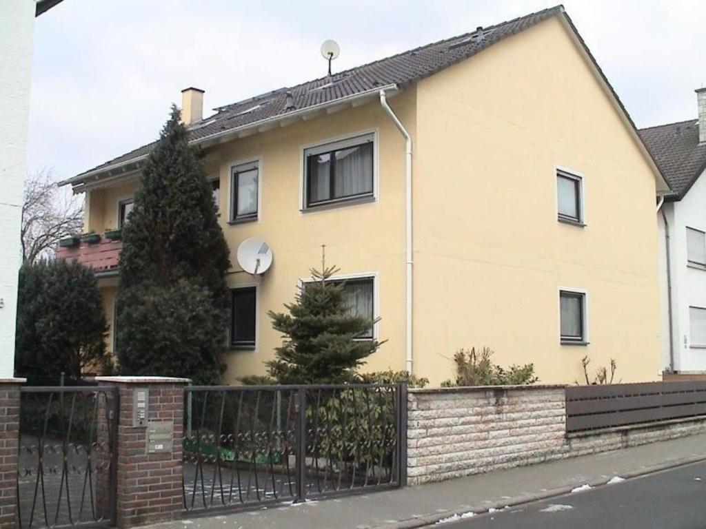 ein gelbes Haus mit einem Zaun davor in der Unterkunft Tolles Appartement in Hanau in Hanau am Main