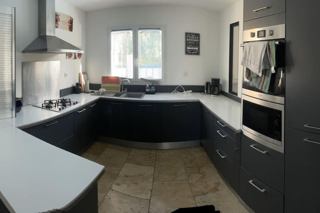 a kitchen with black cabinets and white counter tops at Villa 200m2, 3 suites, patio avec salle jeux, 1 piscine CHAUFFE DE DEBUT AVRIL A FIN OCTOBRE in Maruéjols