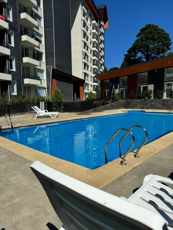 a swimming pool with lounge chairs in a building at Depto hermosa vista al Lago y Volcán in Villarrica