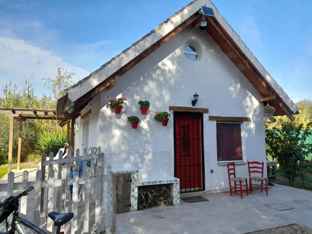ein kleines weißes Cottage mit einer roten Tür in der Unterkunft La Barraca de Ro-Casa en el campo con piscina-50 kilimetros de la playa in La Ñora