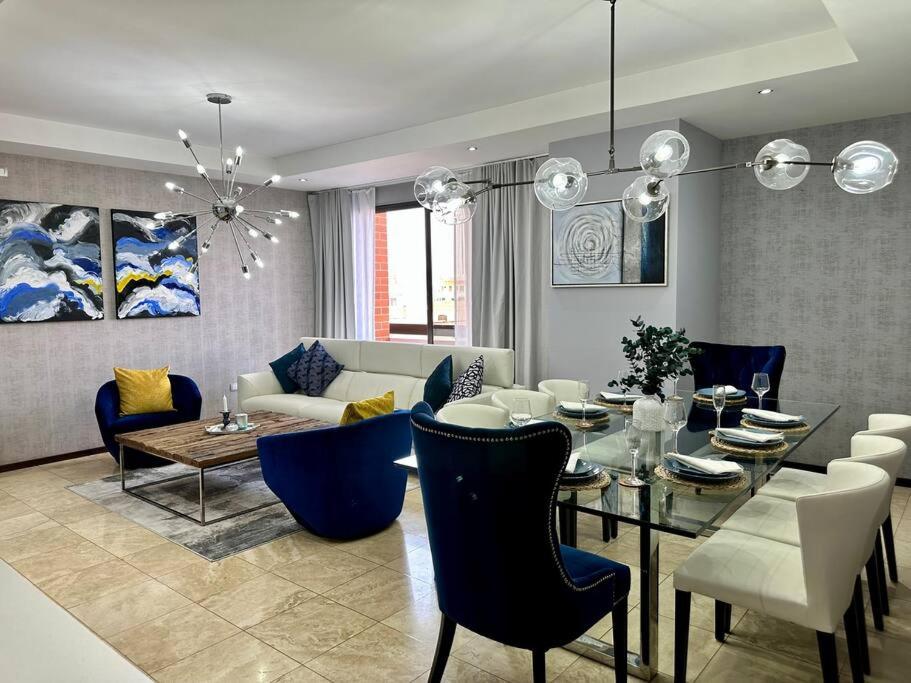 a living room with a glass table and blue chairs at Metropolitan Blue SK in Guatemala