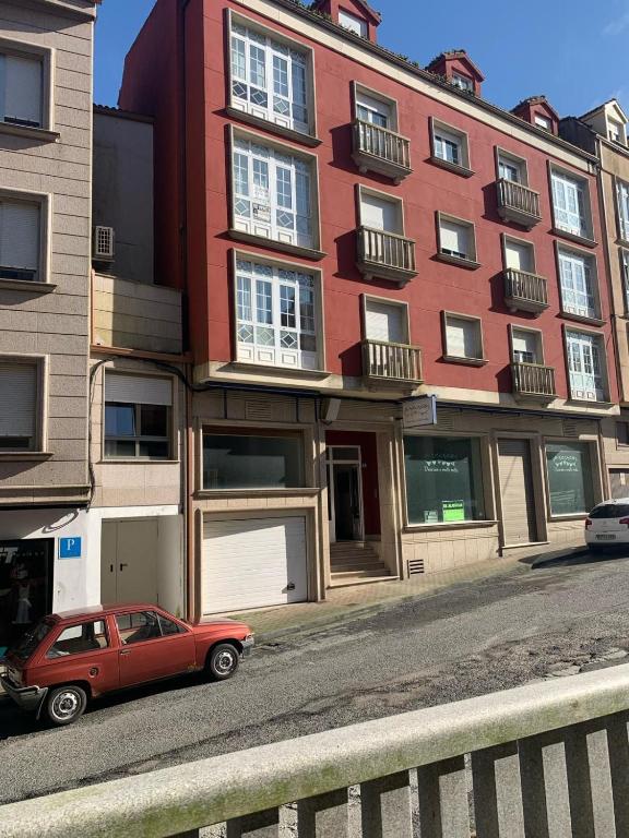 a red car parked in front of a red building at Apartamento Castiñeira in Fisterra