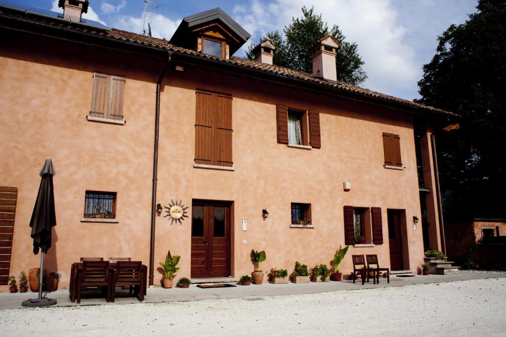 a building with chairs and an umbrella in front of it at B&B Al Sole Di Cavessago in Belluno