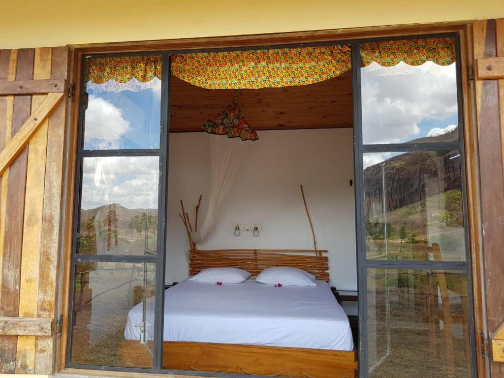 Serra de São BentoにあるPousada Fulô da Pedraの窓付きの部屋にベッド付きのベッドルーム1室があります。