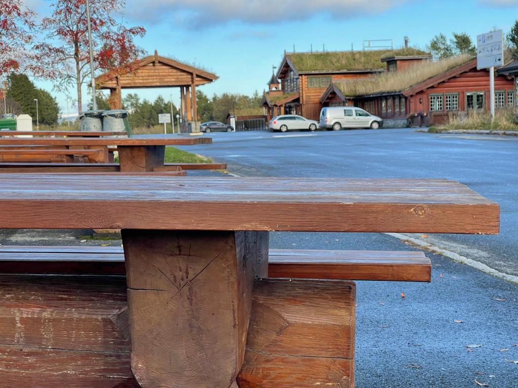 a wooden picnic table in front of a parking lot at Oppdalsporten Motell in Oppdal