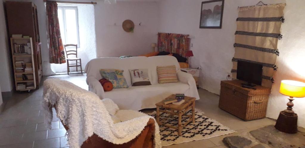 ein Wohnzimmer mit einem weißen Sofa und einem TV in der Unterkunft Le Montadou in Coucouron