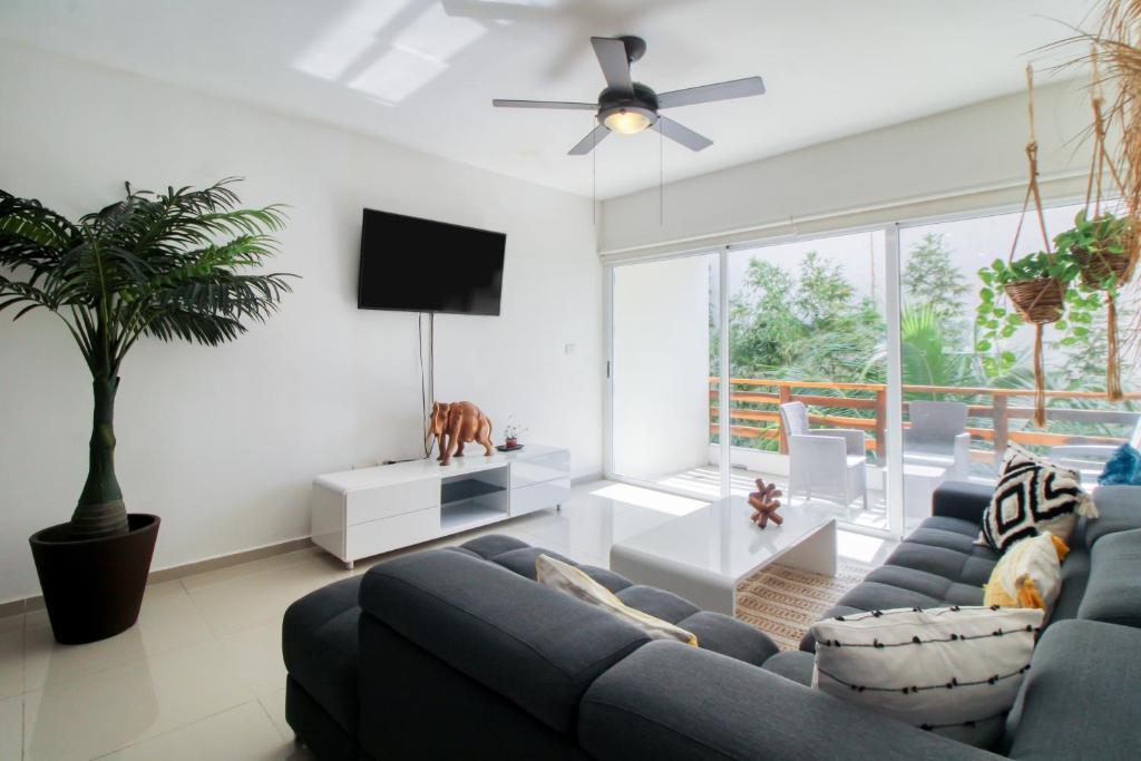 Una sala de estar con un sofá azul y un televisor en The Restful Elephant @ Sabbia D409, en Playa del Carmen