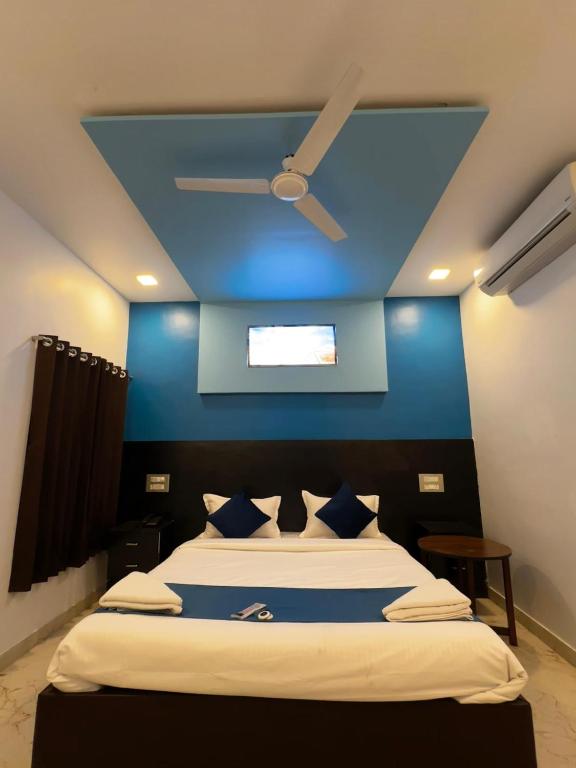 a bedroom with a blue wall and a bed with a ceiling at Golden Pearl Resort By Gemstone Hospitality in Alibag
