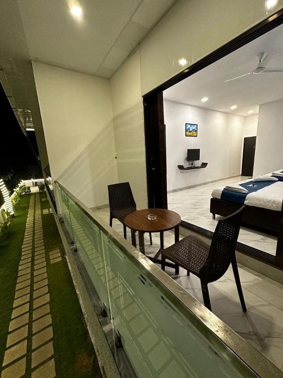 a balcony with a bedroom and a bed and a table and chairs at Golden Pearl Resort By Gemstone Hospitality in Alibag