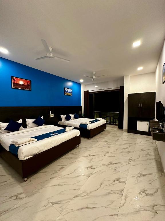 a room with three beds and a blue wall at Golden Pearl Resort By Gemstone Hospitality in Alibag