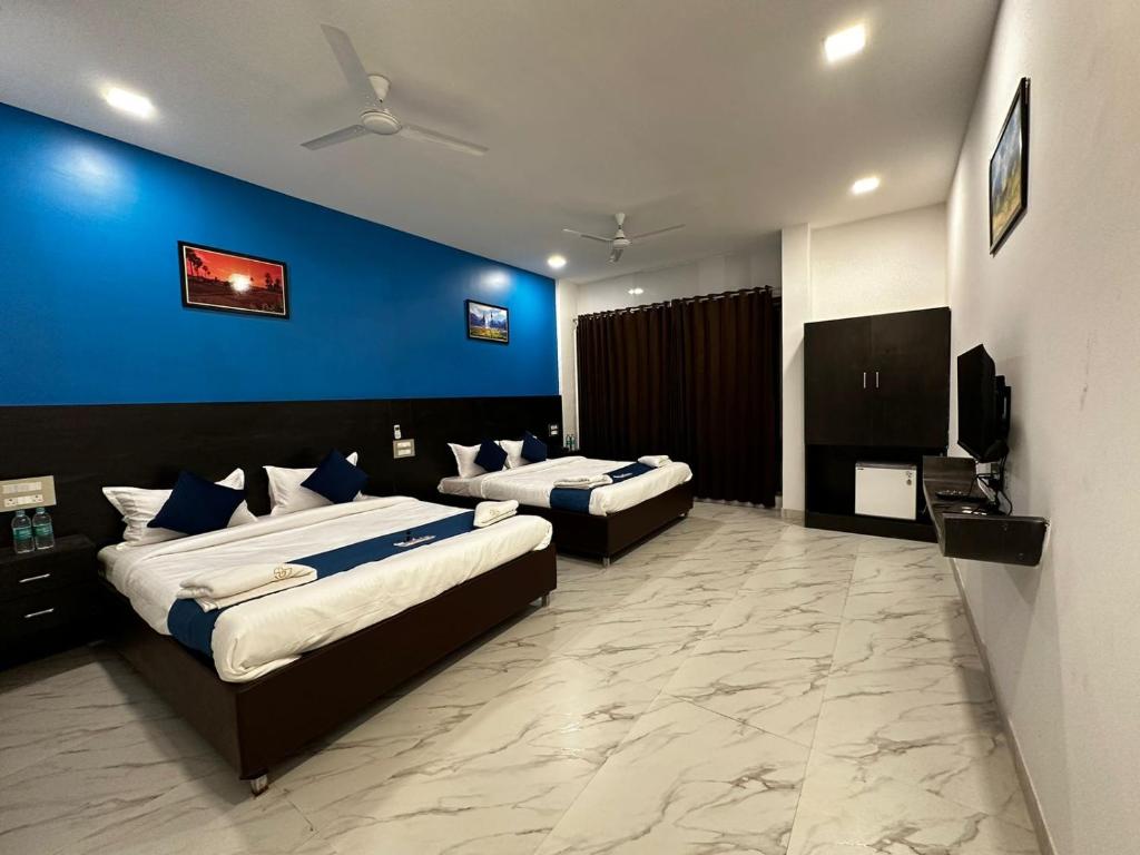 a bedroom with two beds and a blue wall at Golden Pearl Resort By Gemstone Hospitality in Alibag