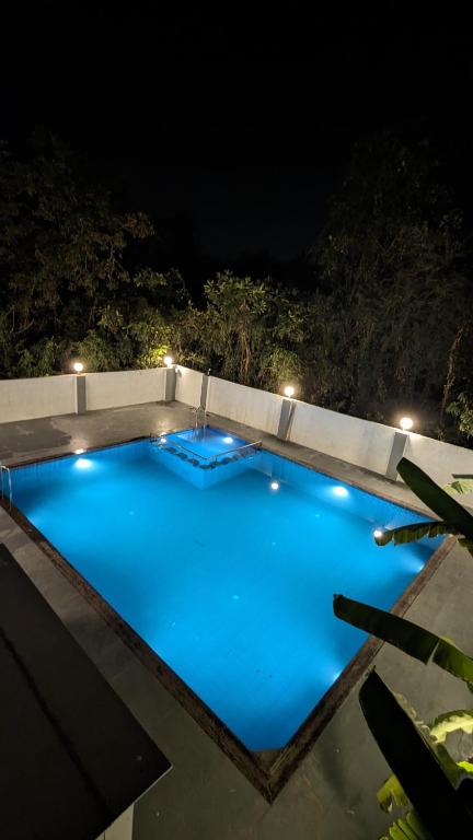 a large blue swimming pool at night with lights at Golden Pearl Resort By Gemstone Hospitality in Alibag